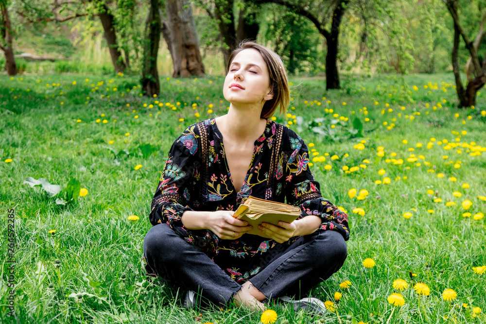 Young caucasian woman with book on meadow with dandelions. Young caucasian woman with book on meadow with dandelions.