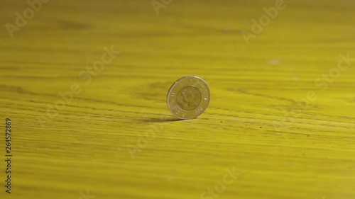 Slow Motion Close Up Canadian Toonie Coin Spinning Circles On Wooden Table photo