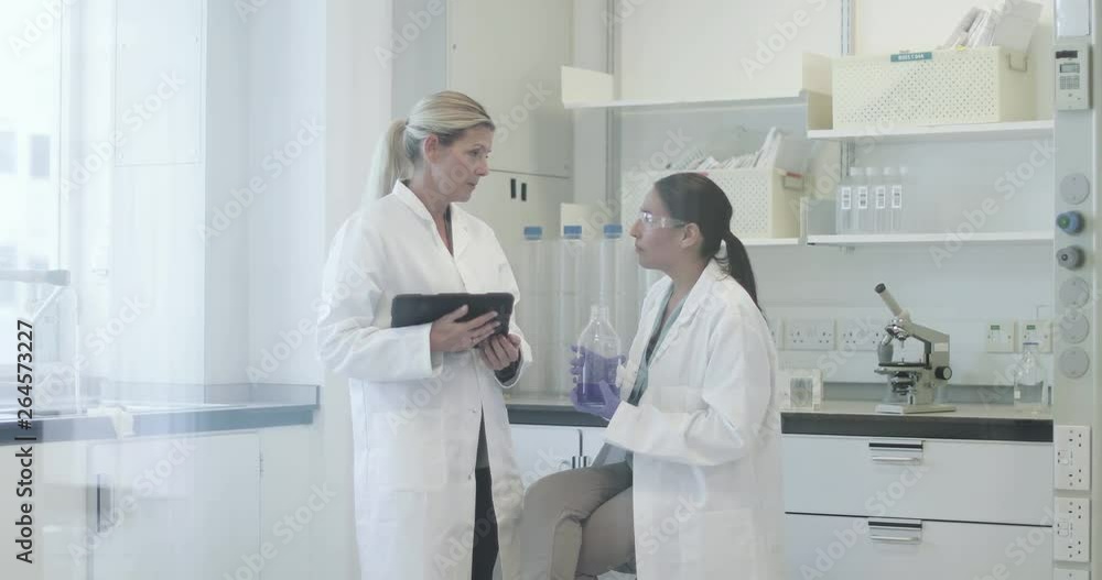Two female scientists analyzing data on digital tablet Two female scientists analyzing data on digital tablet