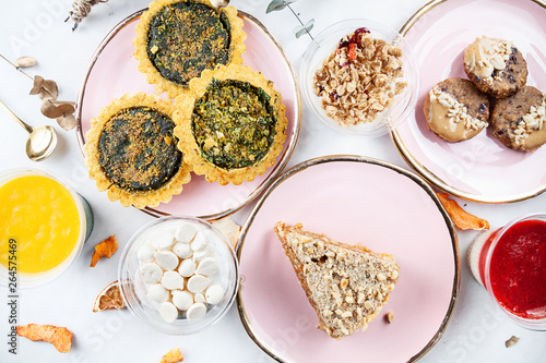 Top view on served food table. Healthy vegan pastry, dessert on marble table. quiche, cookie, cake, trifle, granola. Copy space for design. Healthy breakfast flat lay
