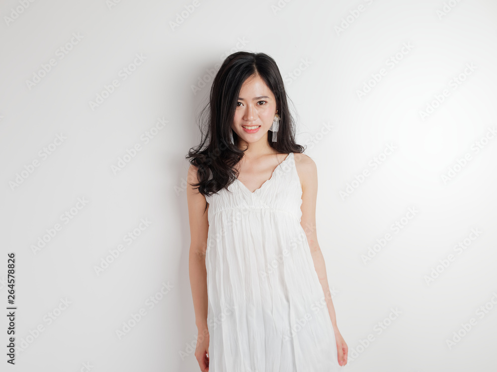 Portrait of beautiful Chinese woman in sexy white dress posing with white wall background, young girl looking and smiling at camera with hands on body side. Portrait of beautiful Chinese woman in sexy white dress posing with white wall background, young girl looking and smiling at camera with hands on body side.