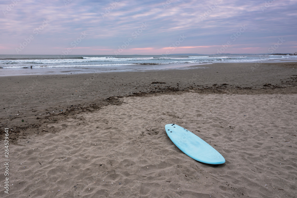 Surf board on a sandy beach at La Grande Motte french city under sunset light. France 2019. Surf board on a sandy beach at La Grande Motte french city under sunset light. France 2019.