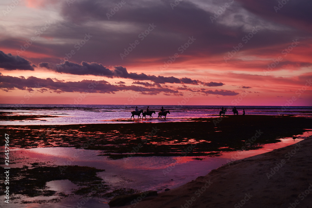Tourists riding horses and enjoy a spectacular sunset on the island of Gili Trawangan Lombok Indonesia