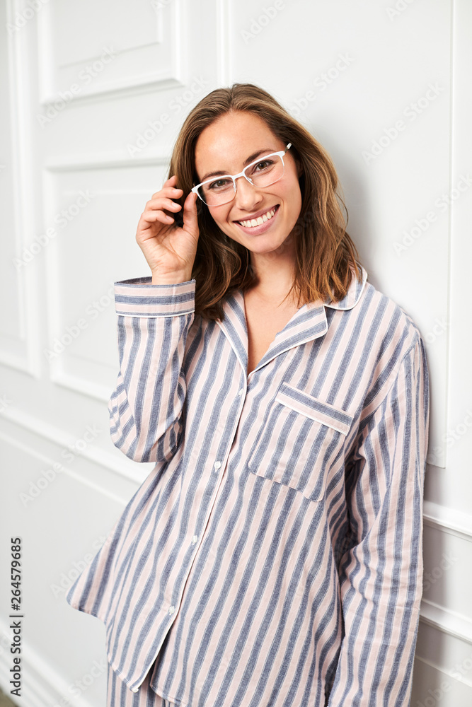 Pretty girl in striped pajamas, adjusting glasses Pretty girl in striped pajamas, adjusting glasses