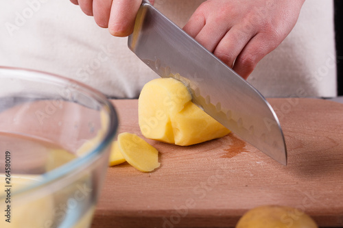 young woman in an apron cuts potatoes