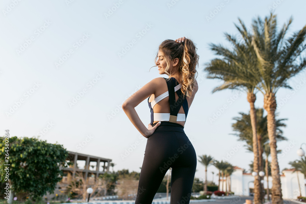 Φωτογραφία View from back joyful amazing happy woman in sportwear in tropical city