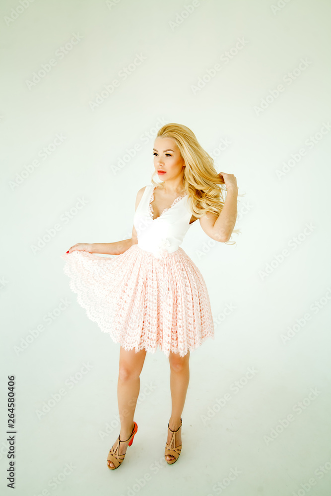 girl model blonde with a wreath of flowers on her head in pink dress isolated on white background