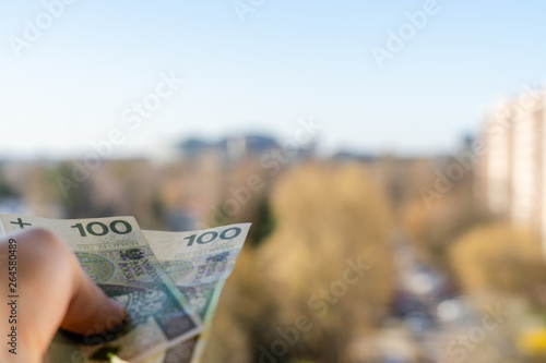 Banknotes held in the palm of your hand symbolizing the social distribution. In the background you can see blurred buildings.