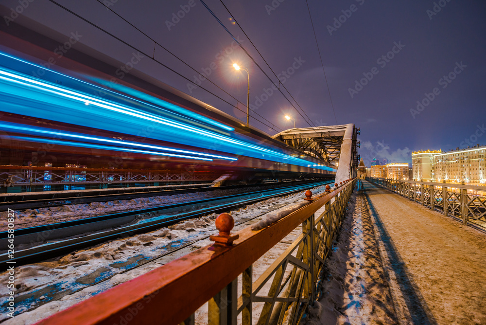 High-speed train with motion blur on the background of the railway bridge in the dark