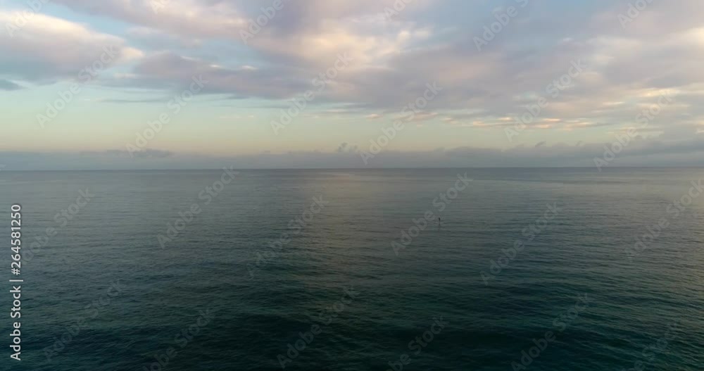 4k aerial drone shot flying over the ocean with a stand up paddler in the distance 4k aerial drone shot flying over the ocean with a stand up paddler in the distance