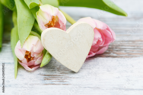 white Heart with pink flowering tulips on wood
