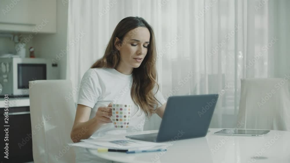Woman using laptop computer at kitchen. Portrait of business woman watching news Woman using laptop computer at kitchen. Portrait of business woman watching news