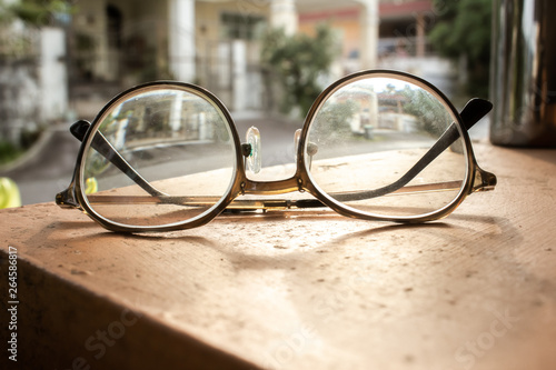 A pair pf round glasses on a surface under the sun.