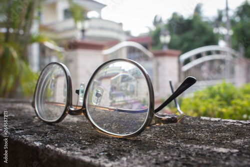A pair pf round glasses on a rough surface under the sun.