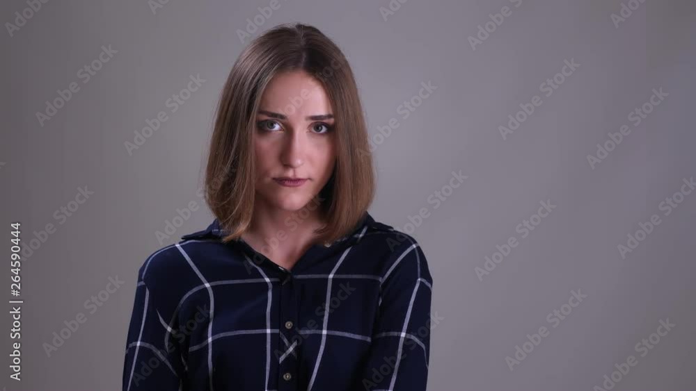 Closeup shoot of young pretty short haired female looking at camera and smiling making funny facial expressions with background isolated on gray Closeup shoot of young pretty short haired female looking at camera and smiling making funny facial expressions with background isolated on gray