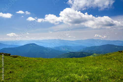 Green mountains panorama under blue sky on bright sunny day. Tourism and traveling concept, copy space background.