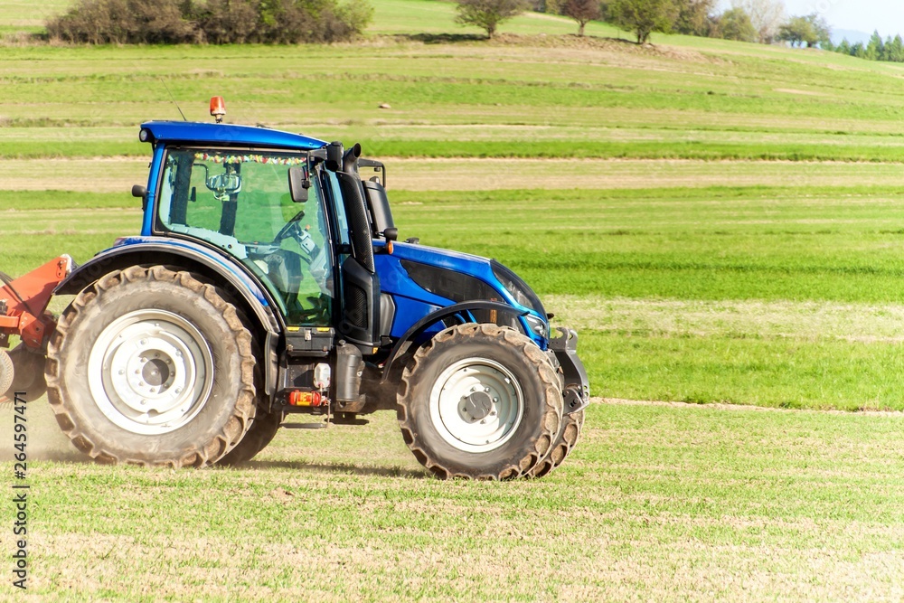 Blue tractor in the field. Working on an agricultural farm in the Czech Republic. Spring work in agriculture. Blue tractor in the field. Working on an agricultural farm in the Czech Republic. Spring work in agriculture.