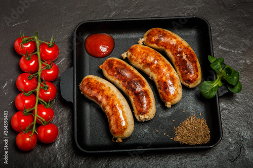 top view square pan with four sausages, ketchup and caraway