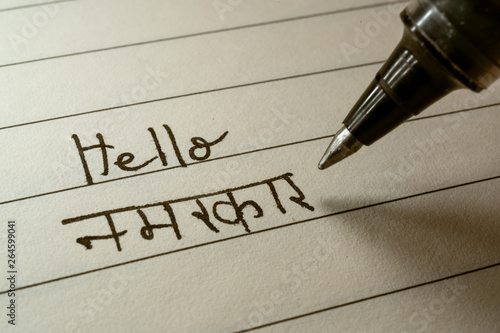 Beginner Hindi language learner writing Hello Namaste word in Indian Hindi alphabet on a notebook photo