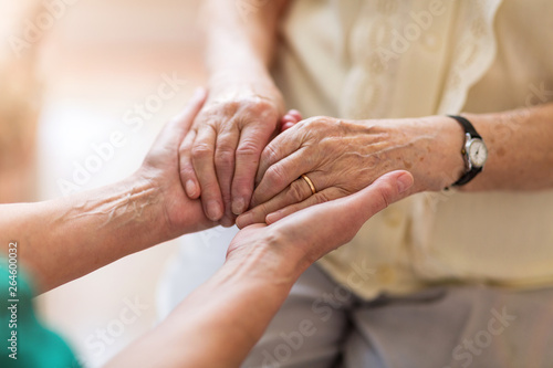 Nurse consoling her elderly patient by holding her hands photo