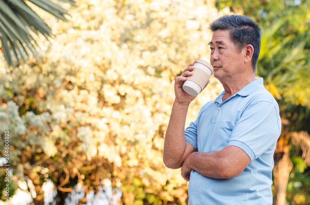 Obraz premium Asian senior gentleman standing in park and drinking coffee with relaxing on a sunny day