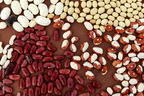 Multicolored collection set of beans, legumes, peas on brown background.