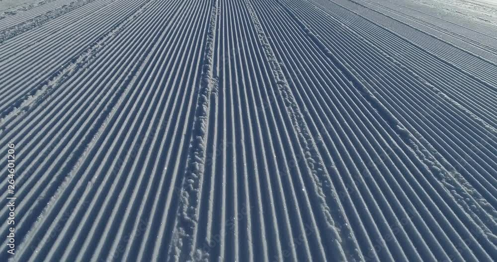 Flying over the ski slope on a frosty sunny day. Ski velvet, snow sparkles. Smooth parallel lines texture. 4K drone footage Flying over the ski slope on a frosty sunny day. Ski velvet, snow sparkles. Smooth parallel lines texture. 4K drone footage