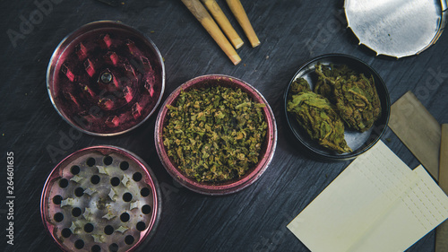 Marijuana buds, joints, paper and lighter lie on dark grey background. photo