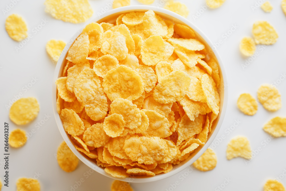 White cup with golden corn flakes, isolated on white background. Hopya crumbled around the cup. View from above White cup with golden corn flakes, isolated on white background. Hopya crumbled around the cup. View from above