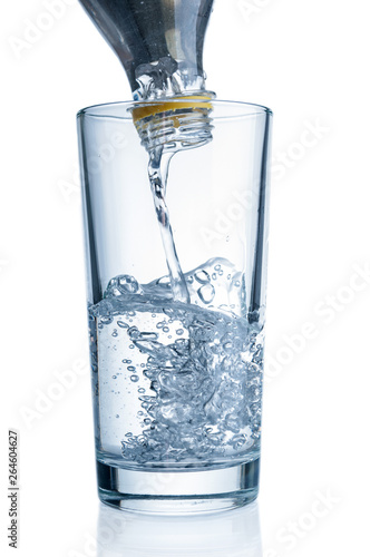 Flowing pure water from bottle into glass on white background