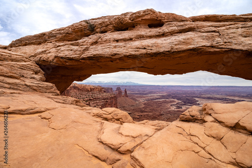 Mid day light shining on Mesa Arch in Canyonlands National Park. Snow capped mountains and canyons can be seen in the distance.  © Scott Heaney