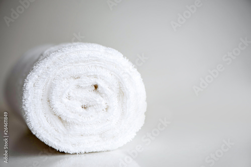White clean, new terry towel twisted into a roll. Spa background in light. Clean white towel rolled blanket textile