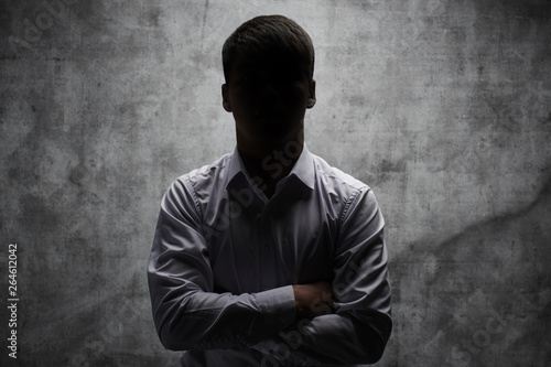 Anonymous man in a business shirt with arms crossed against a dark background