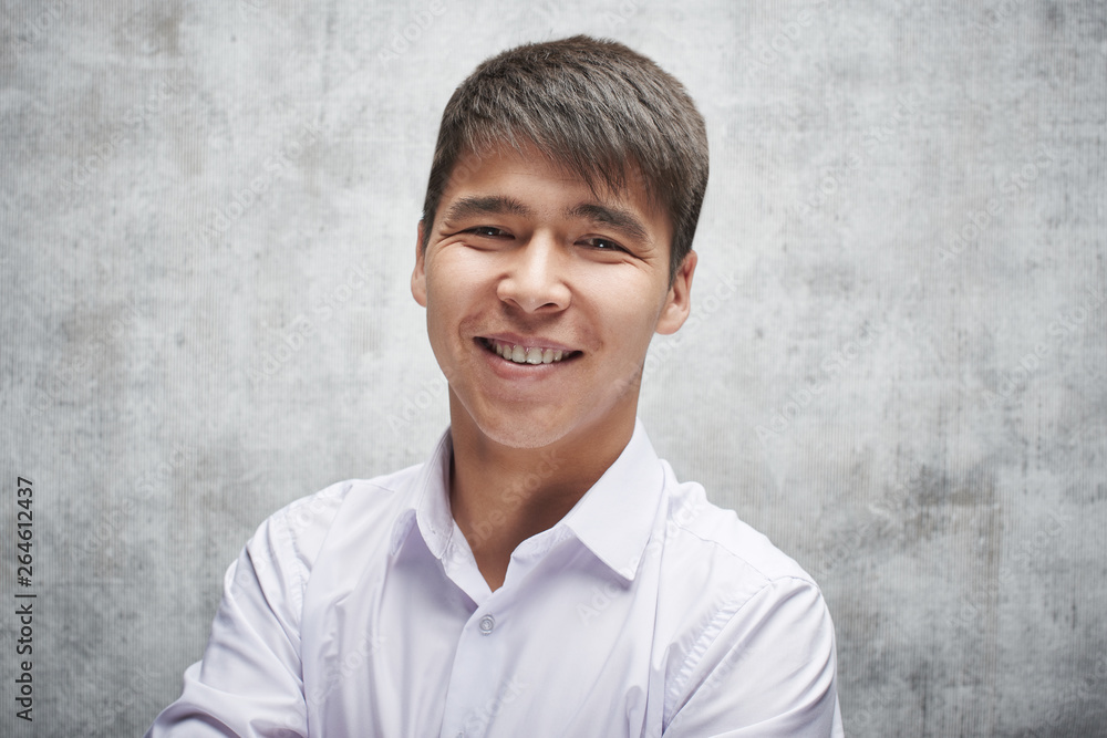 Asian businessman toothy smiling. Portrait of a young attractive Kazakh student in a white shirt in the studio Asian businessman toothy smiling. Portrait of a young attractive Kazakh student in a white shirt in the studio