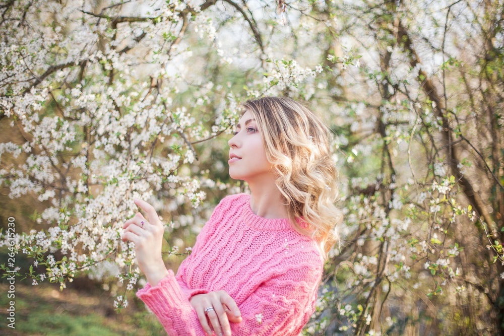 Spring portrait of a young blonde near a flowering tree. Happy young woman. Spring portrait of a young blonde near a flowering tree. Happy young woman.