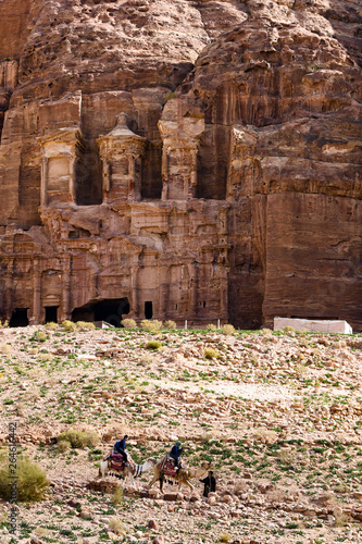 A family is doing a camel tour while a Bedouin is leading them in the beautiful archaeological site of Petra. Petra is a historical and archaeological city in southern Jordan.