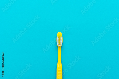 minimalist flat lay photo of yellow toothbrush over turquoise blue background