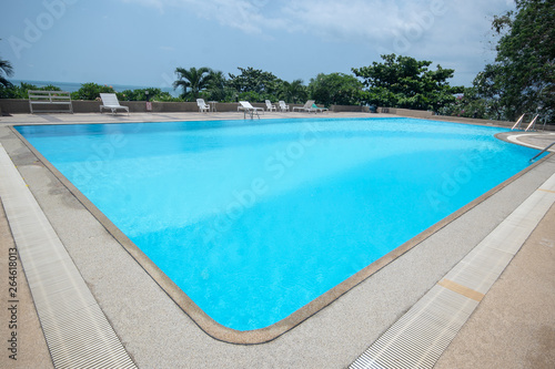 Large rectangular swimming pool against the background of the ocean at the seaside.