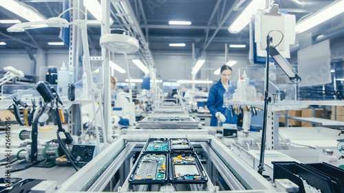 Fényképezés Shot of an Electronics Factory Workers Assembling Circuit Boards by Hand While it Stands on the Assembly Line