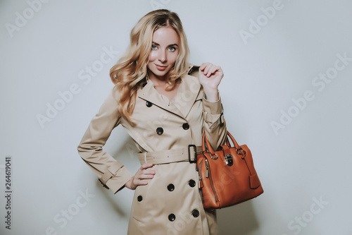 elegant cauccasian woman in beige coat holding brown bag photo