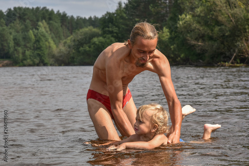 father teaching his little son to swim, they are happy. hot summer day. happy family on the beach.