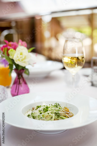 Fresh salad in restaurant with white wine and flowers on the table