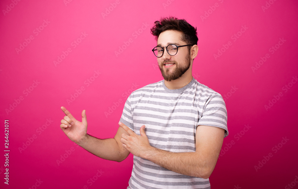Photo of handsome bearded young man pointing away over pink isolated background Photo of handsome bearded young man pointing away over pink isolated background