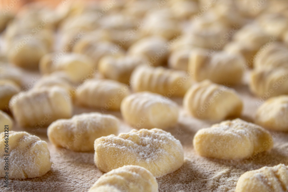 Italian food speciality: hand made potato gnocchi on a wooden board, ready to be cooked. Home made and hand rolled on a fork. Close up, selective focus.