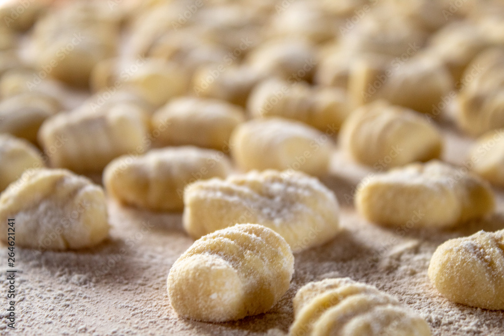 Italian food speciality: hand made potato gnocchi on a wooden board, ready to be cooked. Home made and hand rolled on a fork. Close up, selective focus. Italian food speciality: hand made potato gnocchi on a wooden board, ready to be cooked. Home made and hand rolled on a fork. Close up, selective focus.