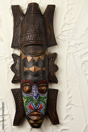 Ashanti carved wood ceremonial mask from Ghana with beads and brass on stucco wall photo