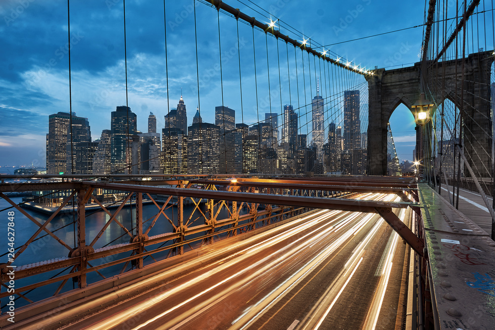 Obraz premium Light trails of passing cars and traffic on the Brooklyn Bridge in New York City