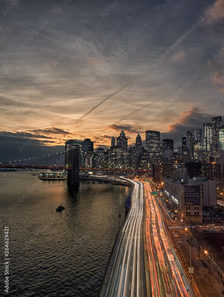 Rush hour traffic on the FDR drive in New York city creating light trails of long exposure just after sunset, seen from the Manhattan Bridge looking towards the Brooklyn Bridge