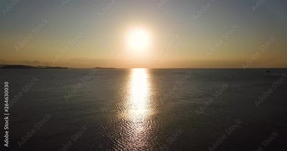Beautiful aerial sunset view with sunlight reflection on the sea water at Elak-Elak Beach in Lombok near Bali, Indonesia. Shot in 4k resolution from a drone flying upwards Beautiful aerial sunset view with sunlight reflection on the sea water at Elak-Elak Beach in Lombok near Bali, Indonesia. Shot in 4k resolution from a drone flying upwards