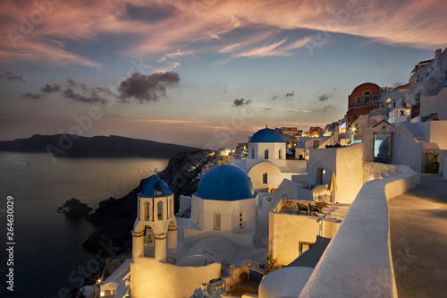 The famous three domes of Oia during beautiful sunset with pink sky on the Greek island of Santorini